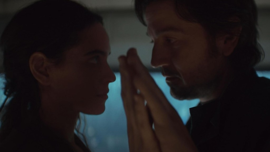 A man and woman touch hands in Andor.